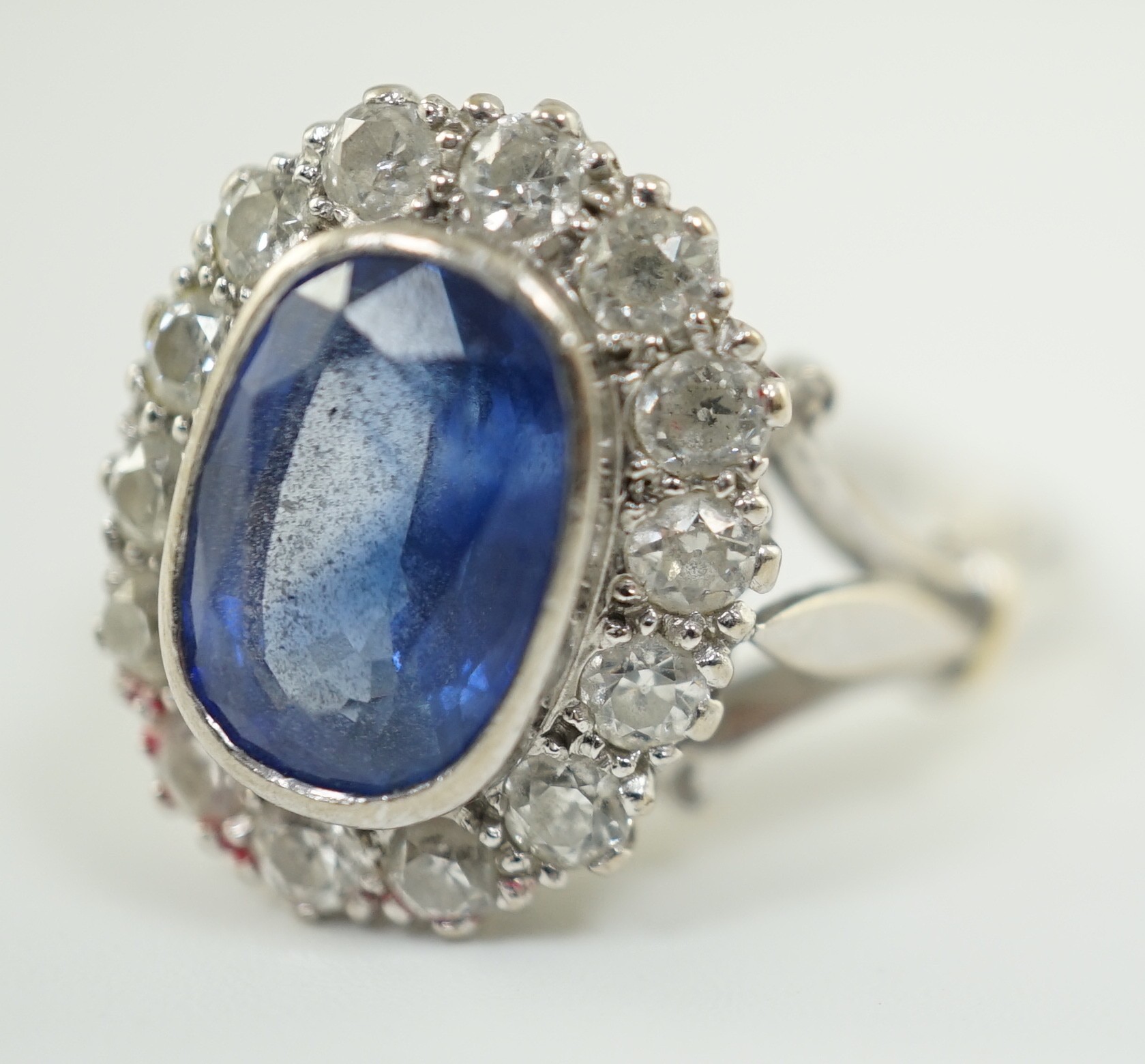 An 18ct white gold, sapphire and diamond set oval cluster ring